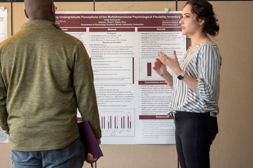Student presenting research poster to judge